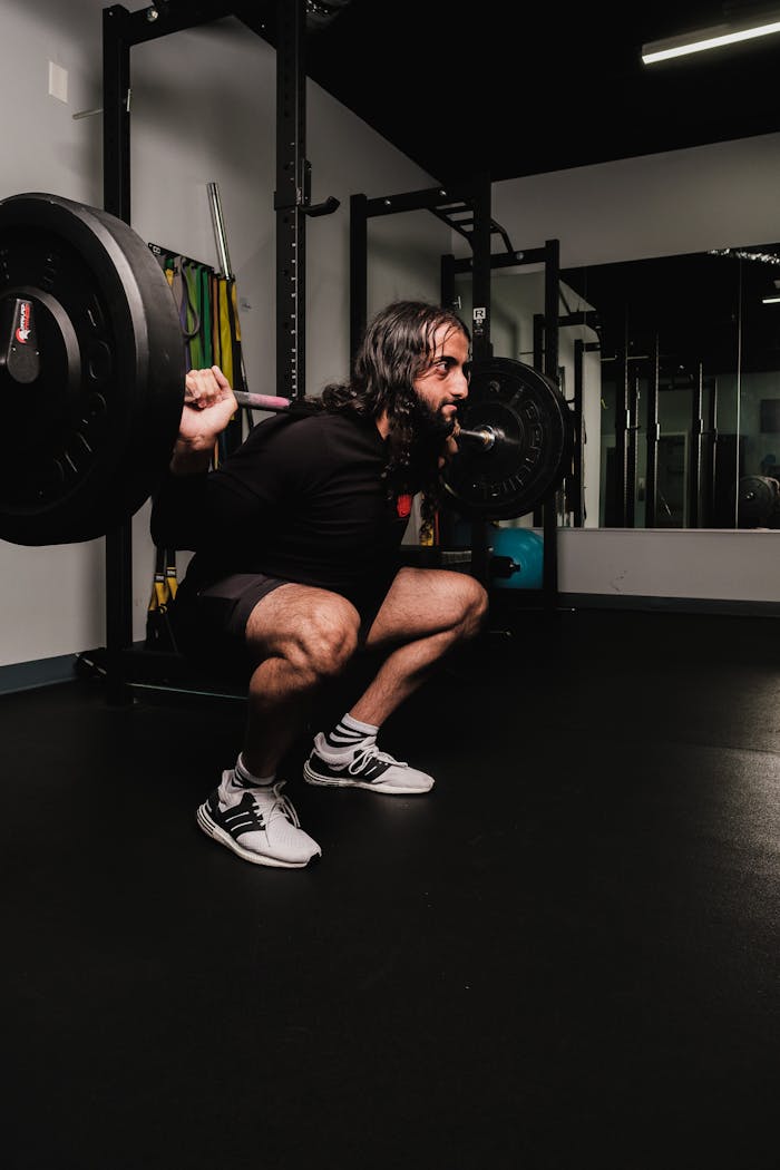 services-04 Mid-adult male lifting weights in a modern gym, focused on strength training.