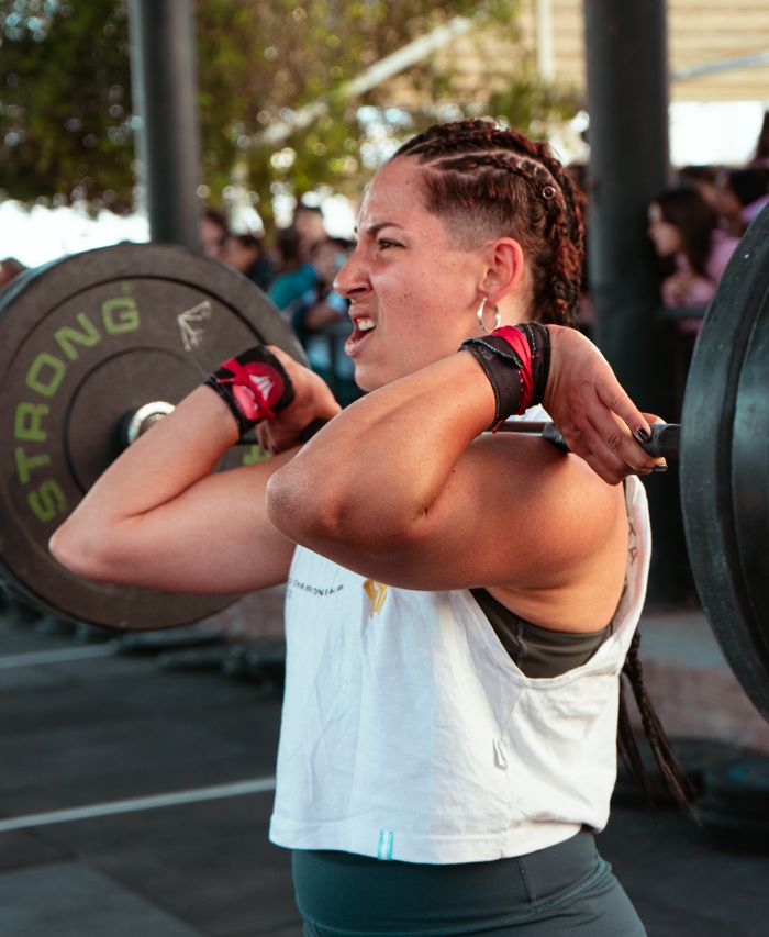 services-01 A determined female athlete lifting weights during an outdoor fitness event.