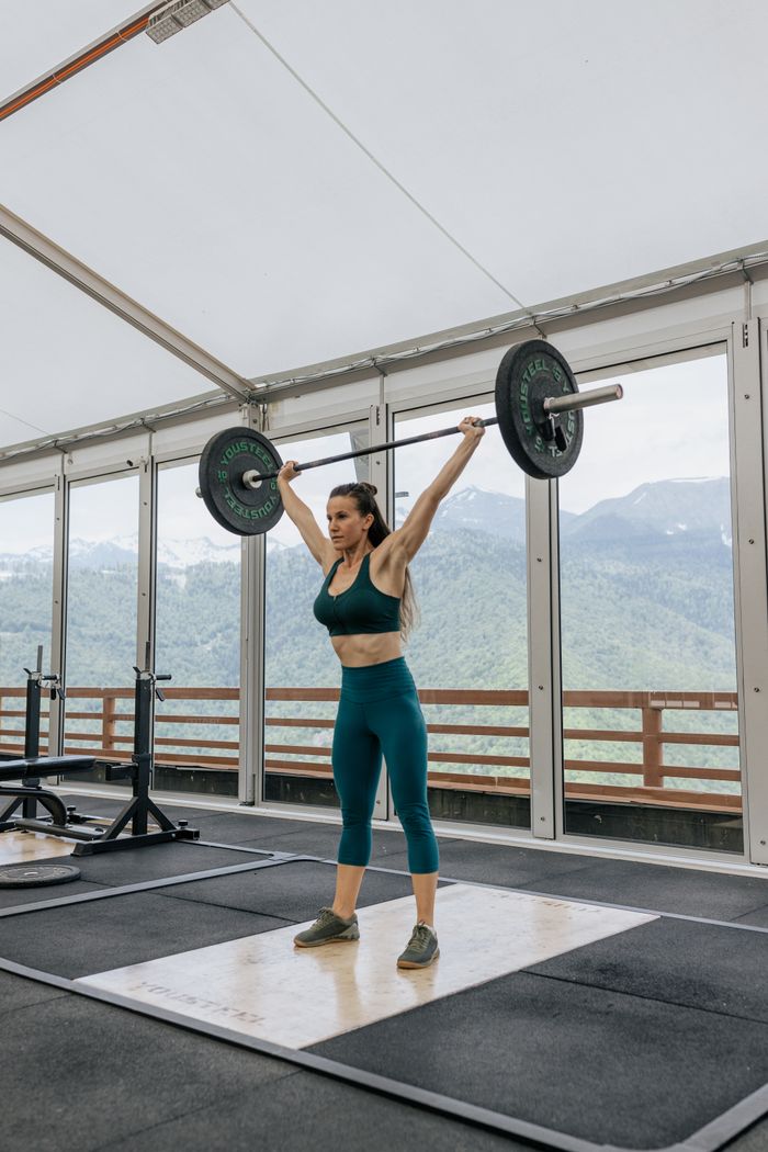 services-03 Strong woman weightlifting in an indoor gym with scenic mountain views.